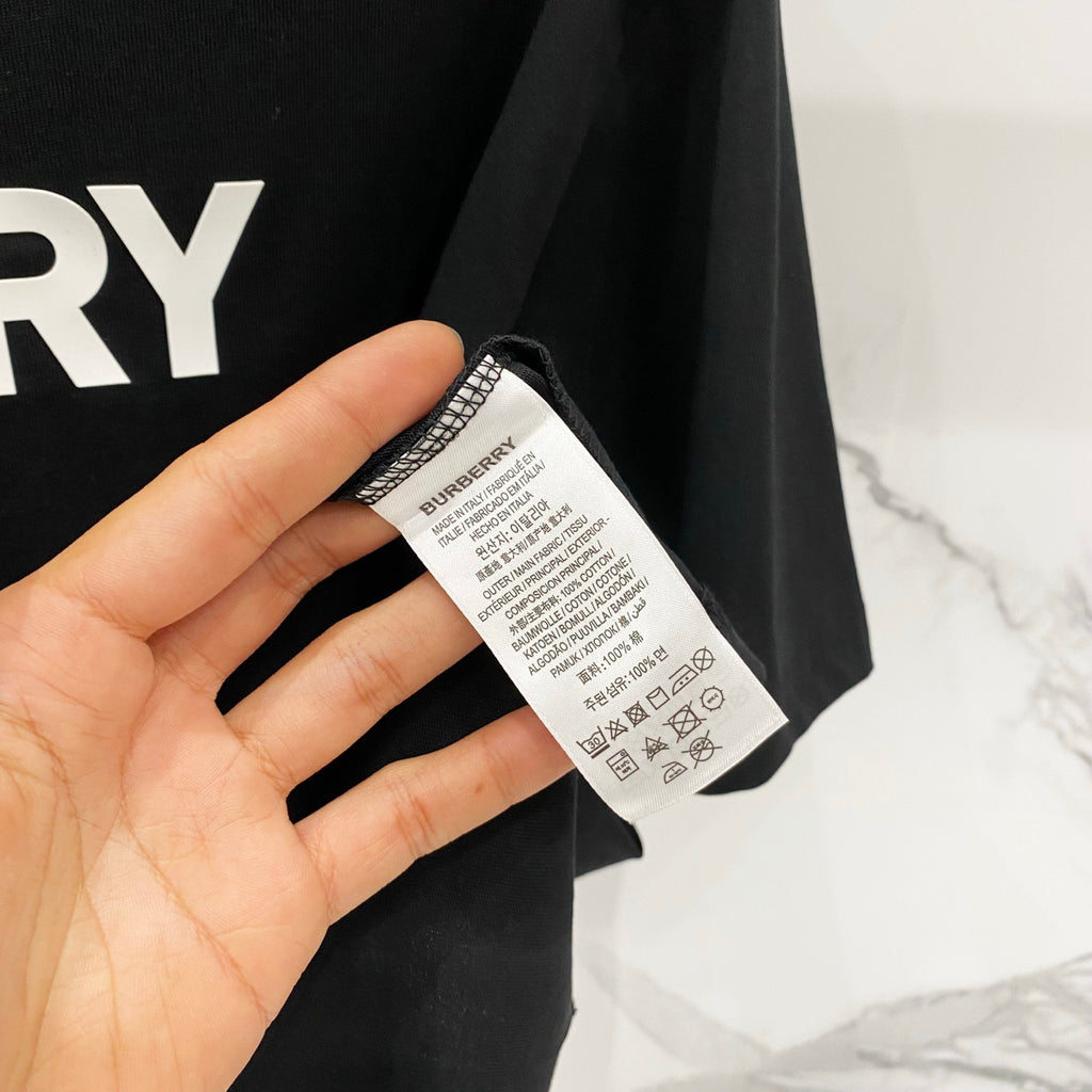 Black T-shirt care label tag with printed instructions near collar