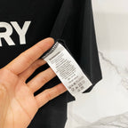 Black T-shirt care label tag with printed instructions near collar