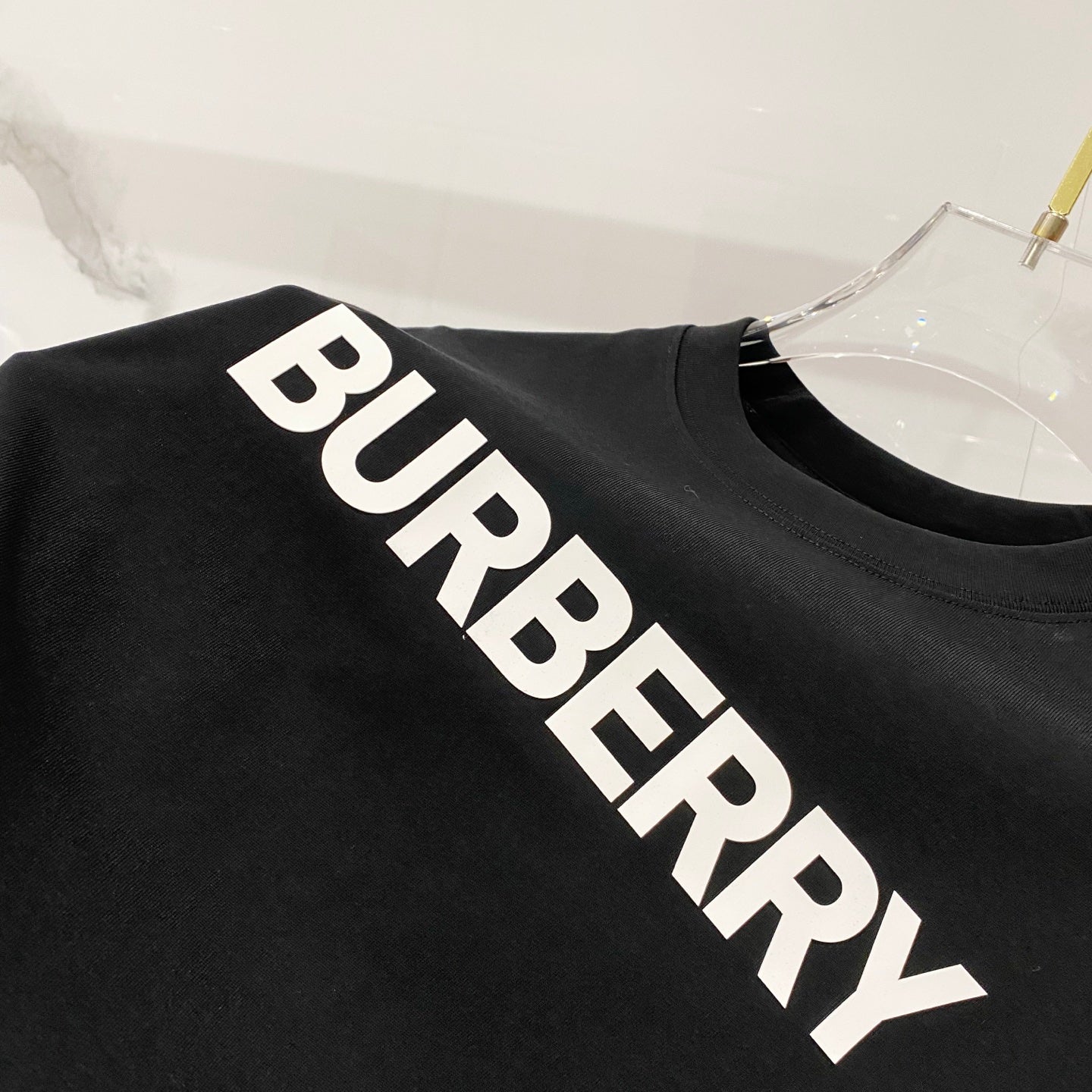 Black T-shirt close-up showing white diagonal BURBERRY lettering