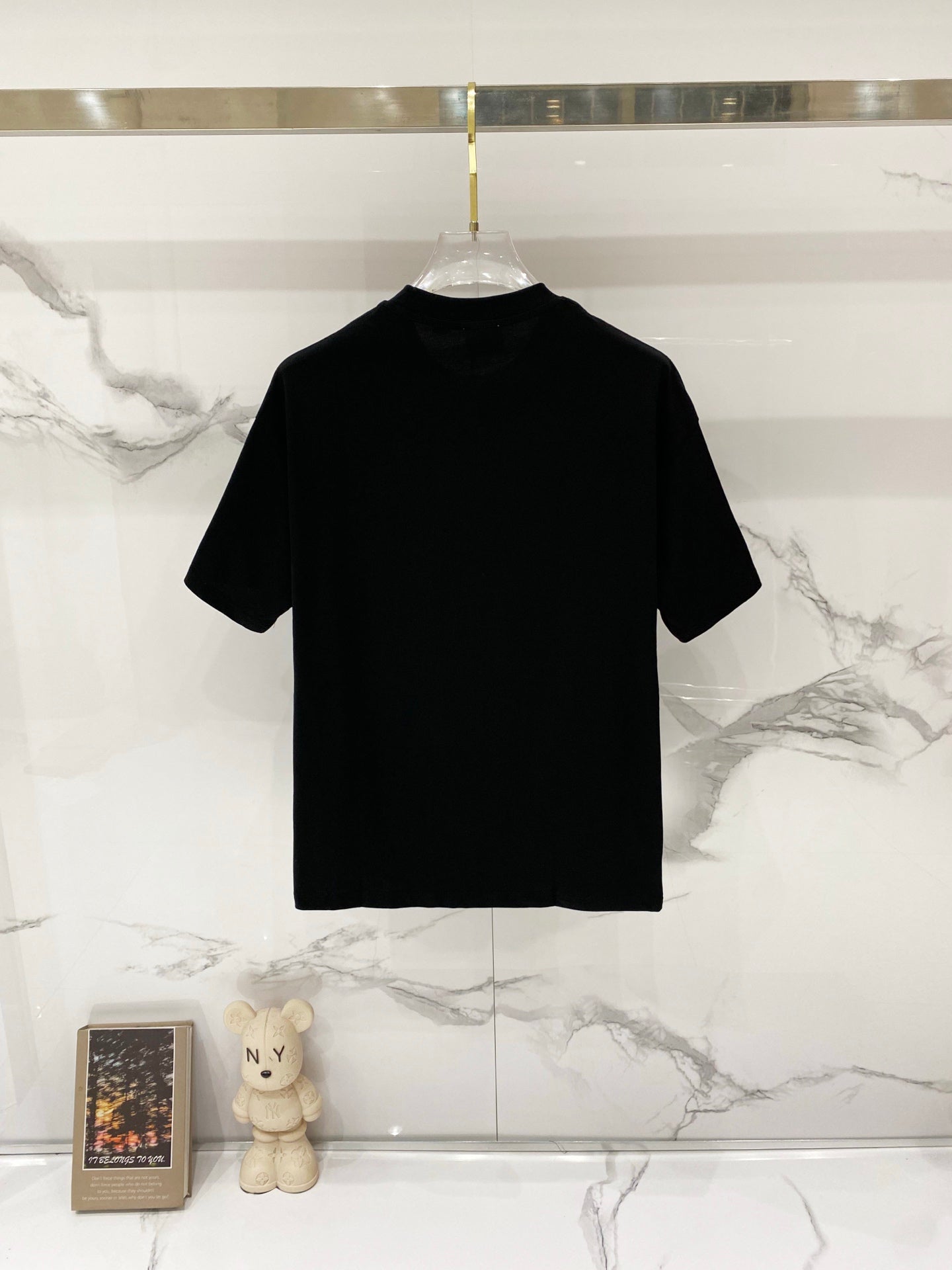 Black crew-neck short-sleeve T-shirt on a clear hanger, plain front