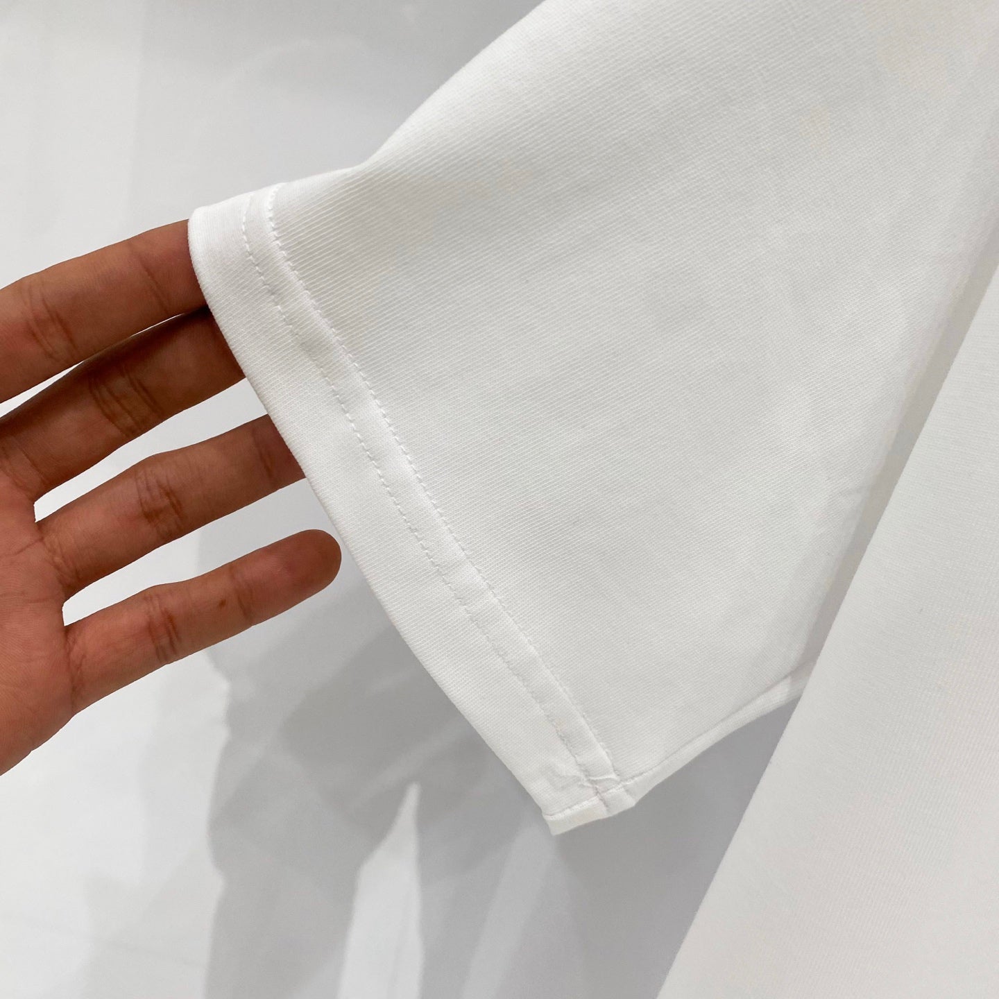 White Burberry short-sleeve T-shirt sleeve hem and cuff detail, held in hand