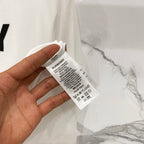 White Burberry short-sleeve T-shirt care label tag held in hand