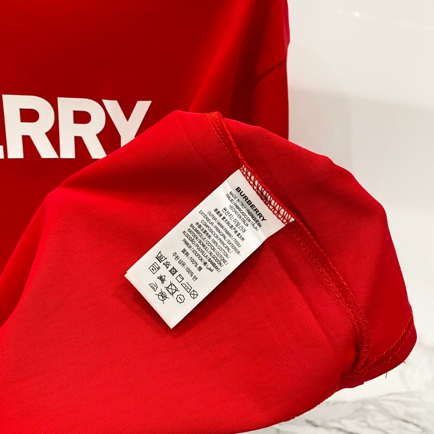 Red Burberry T-shirt care label detail on sleeve
