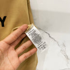 Burberry tan T-shirt fabric tag and care label held in a hand