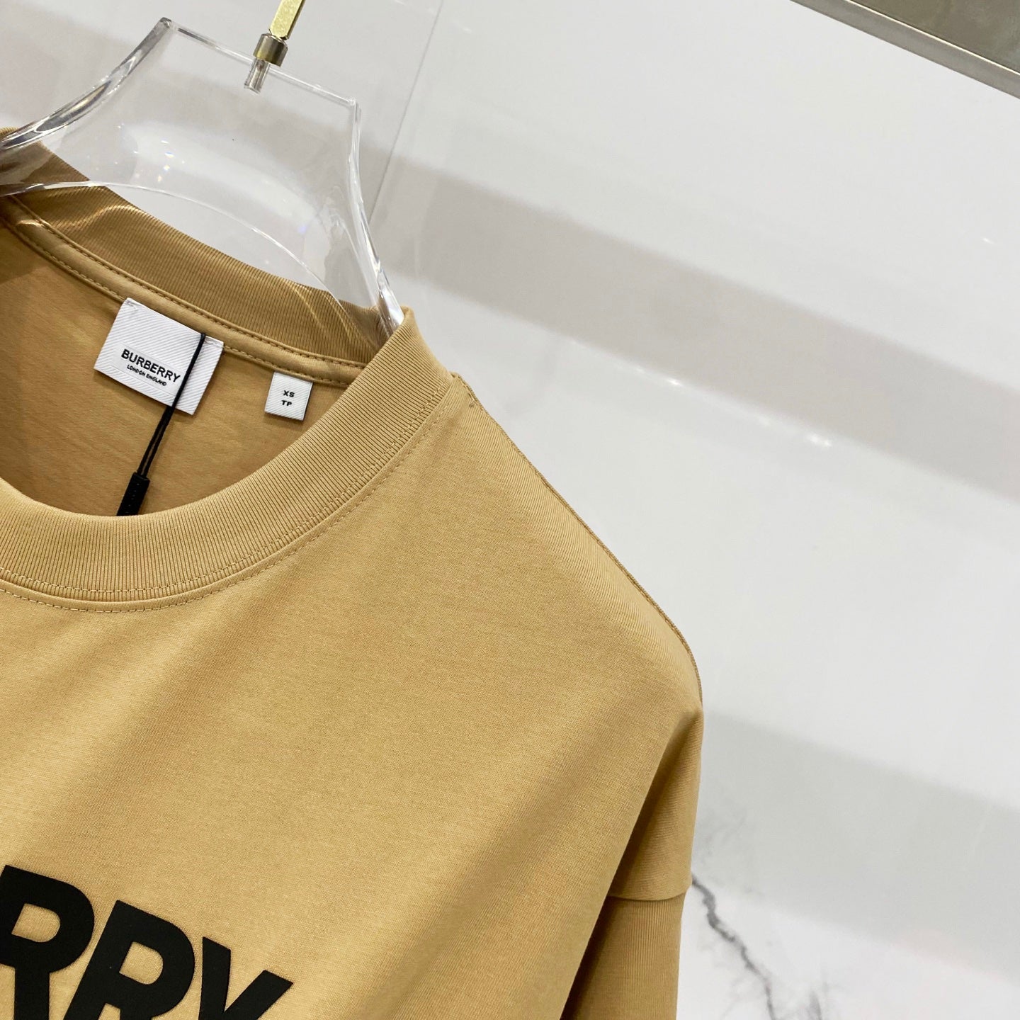Burberry tan T-shirt close-up of collar and partial "BURRY" logo print