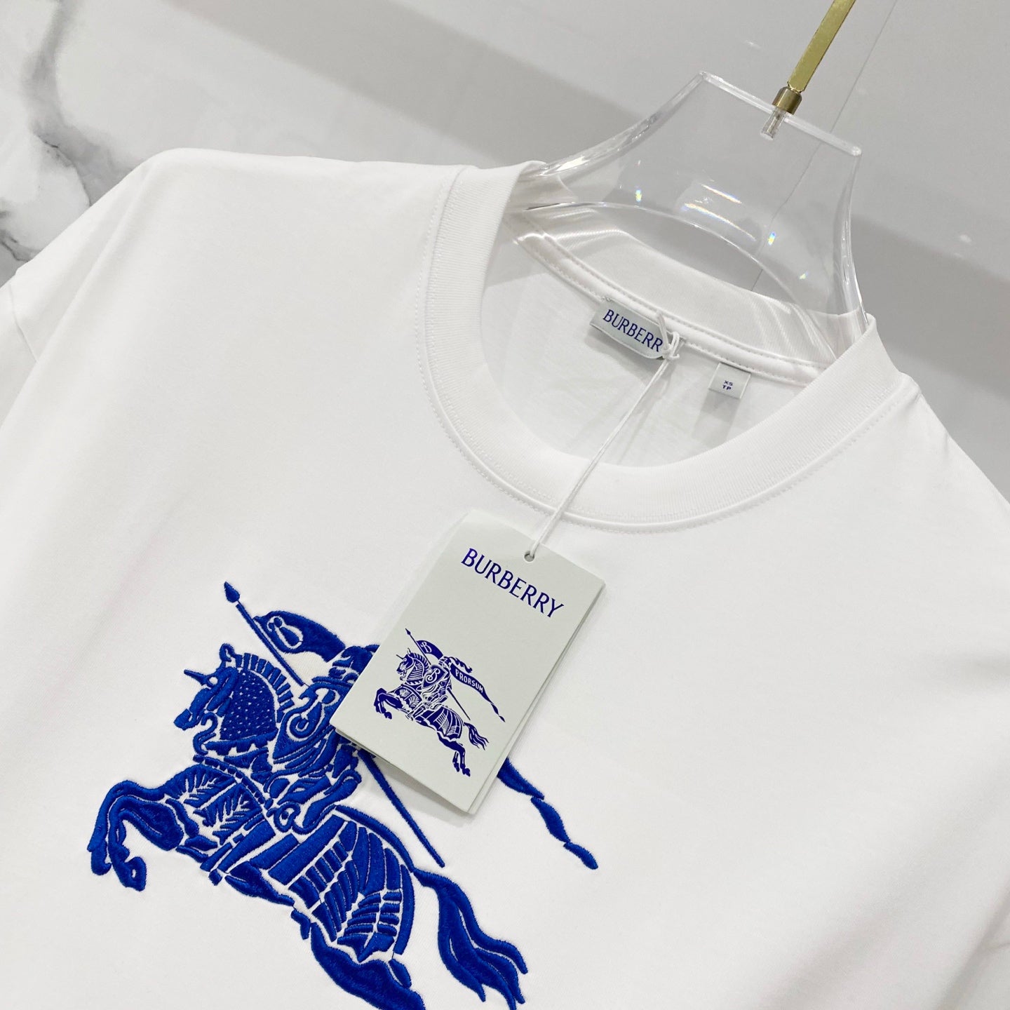 White T-shirt with blue horse rider graphic print and attached brand tags.