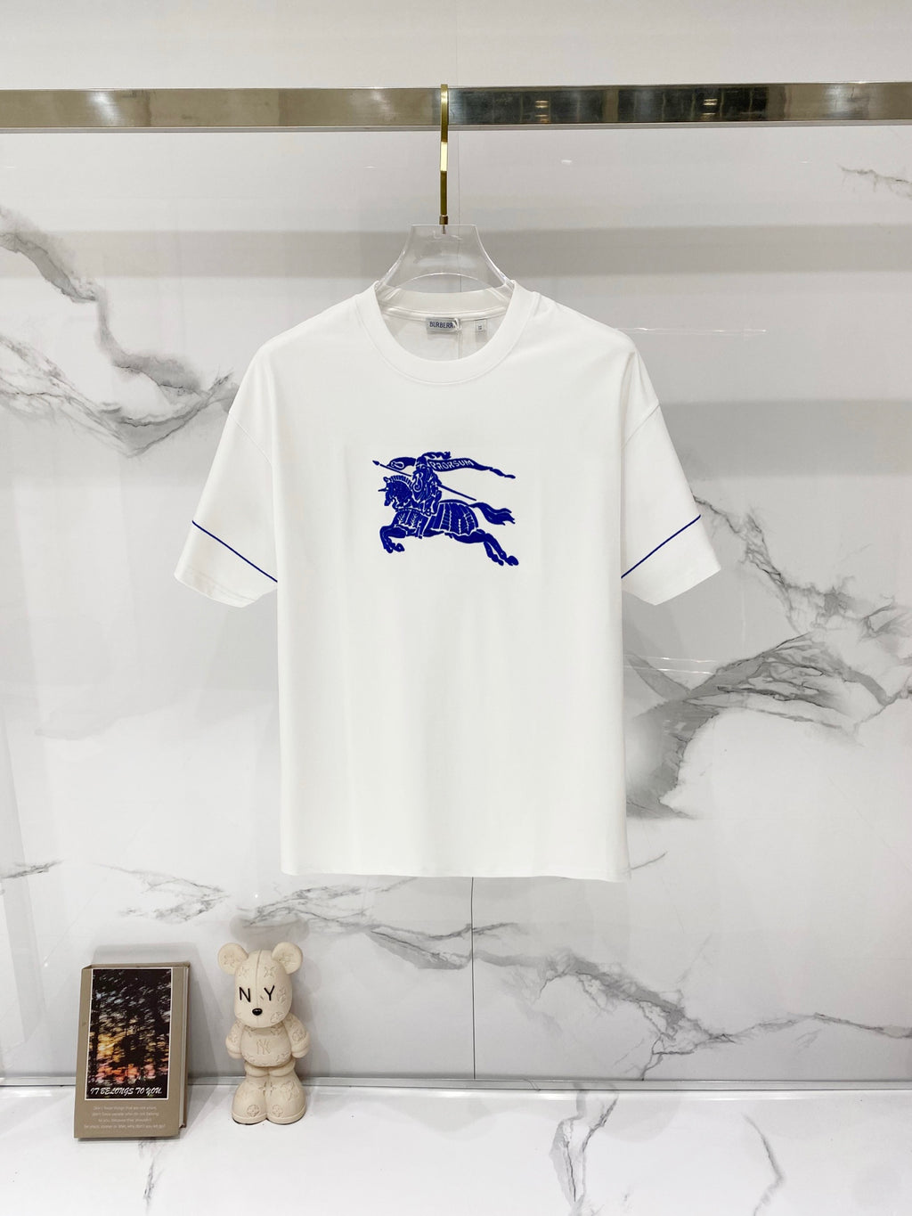 White short-sleeve T-shirt with blue horse rider graphic on the front.