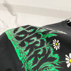 Black Burberry T-shirt graphic closeup with green foliage and daisies