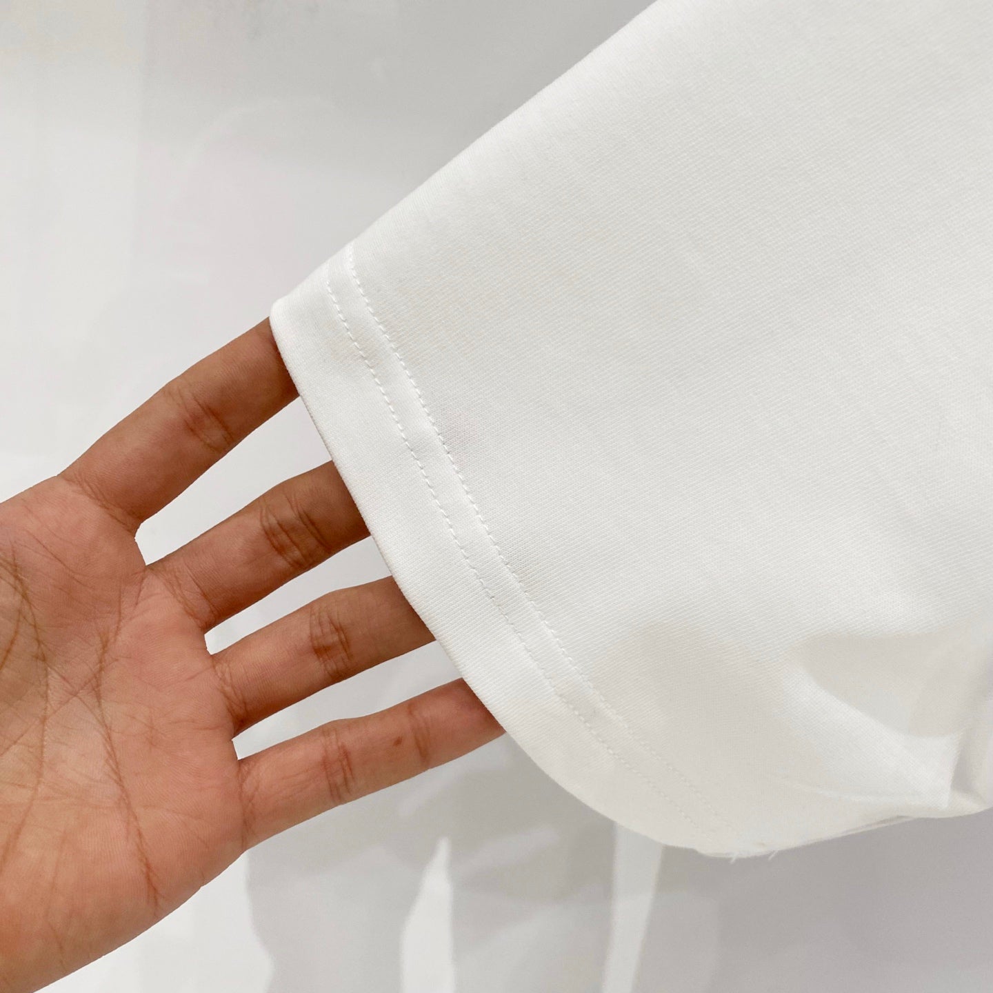 White short-sleeve T-shirt sleeve hem close-up held in hand