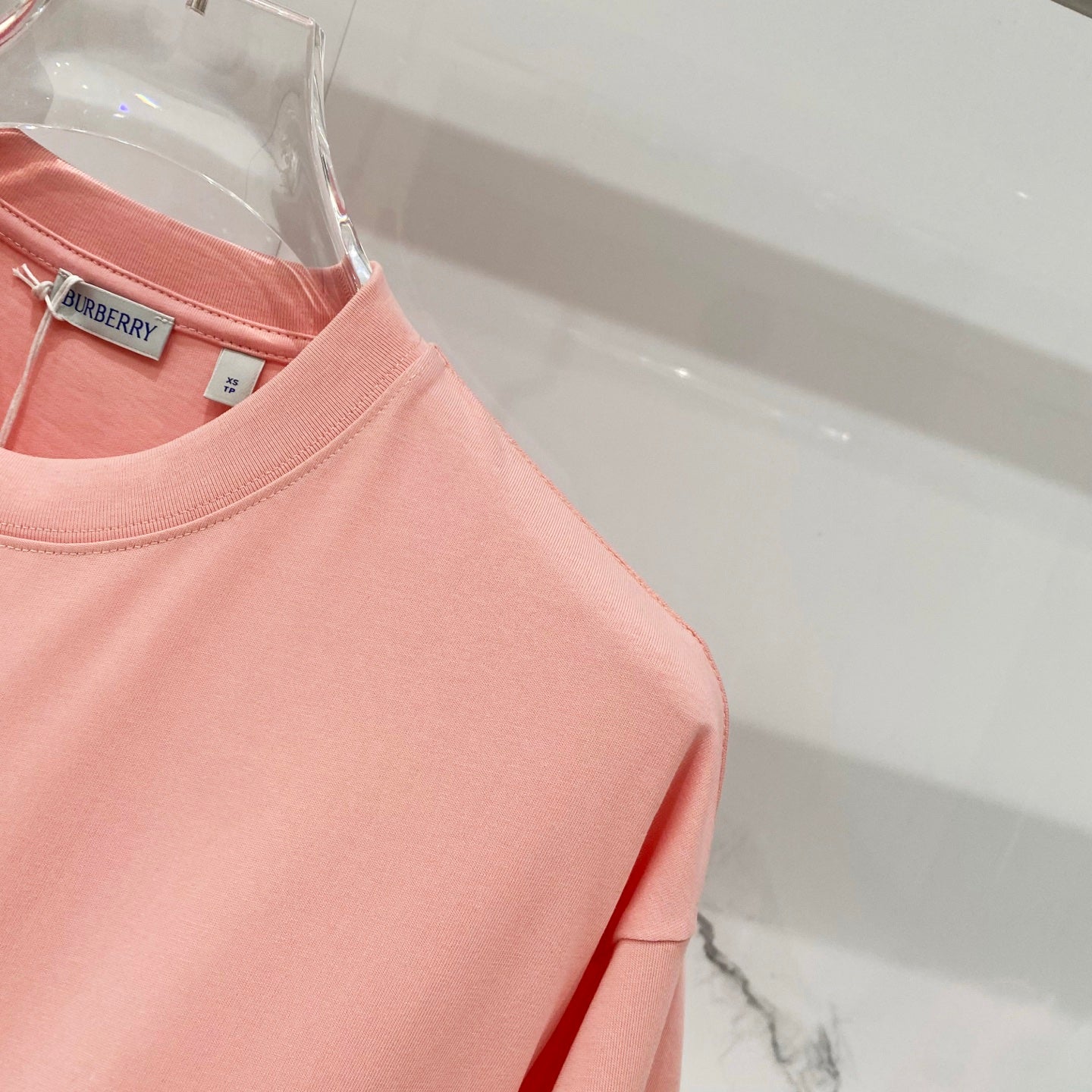Pink Burberry T-shirt shoulder and sleeve seam detail.