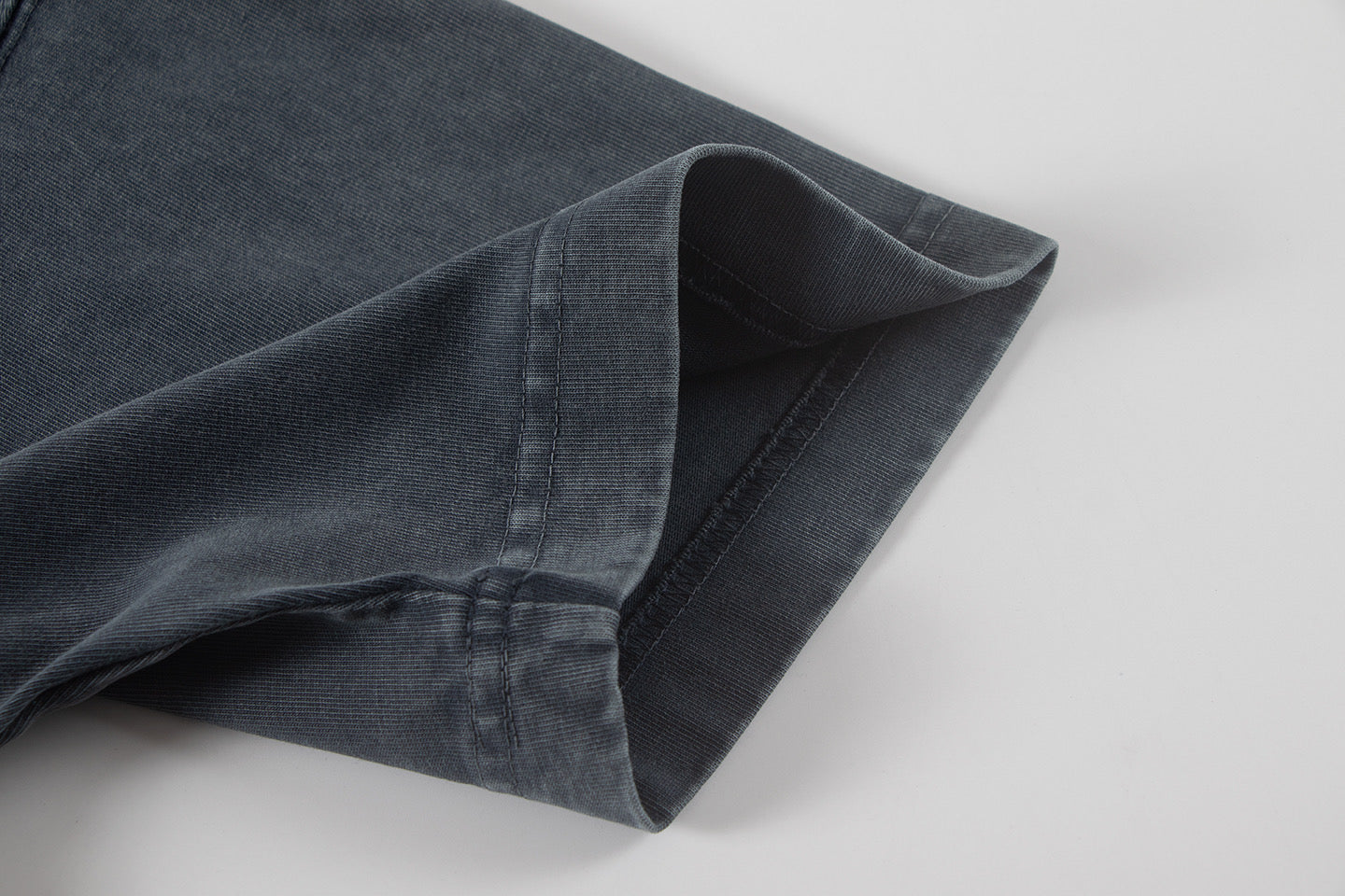 Dark T-shirt short sleeve cuff with visible seam and hem stitching.