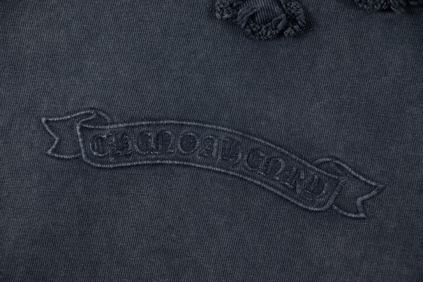 Close-up of dark embroidered text graphic on T-shirt back yoke area.