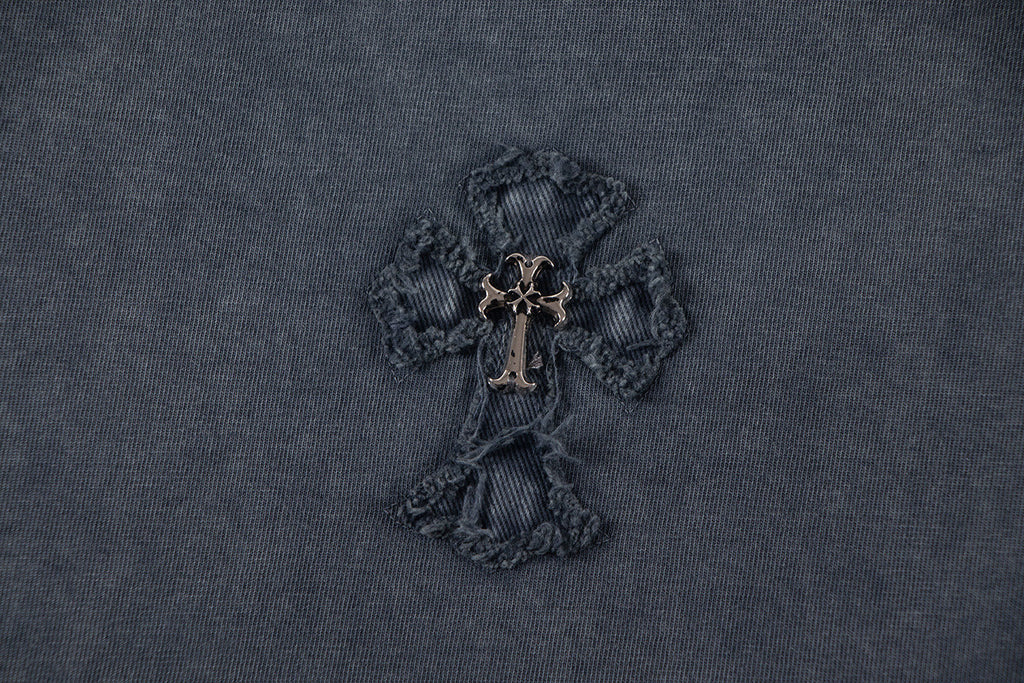 Close-up of dark embroidered cross-like emblem with gold-toned center.