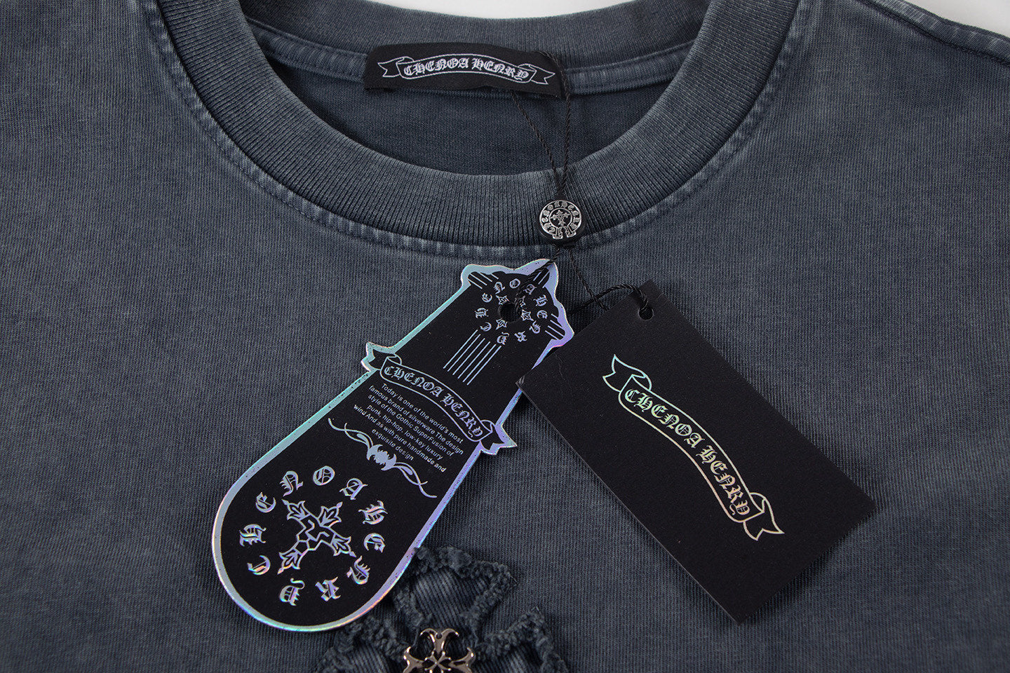 Dark T-shirt neckline with round collar, coin clasp, and inner label.