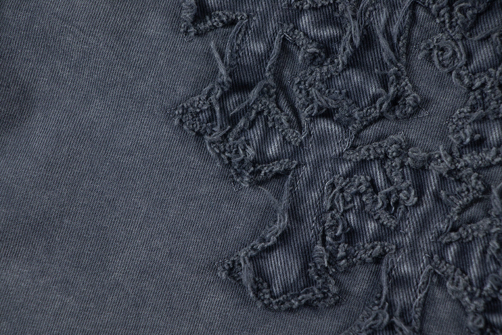 Close-up of dark embroidered floral patch detail on T-shirt fabric.