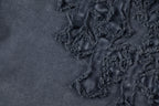 Close-up of dark embroidered floral patch detail on T-shirt fabric.