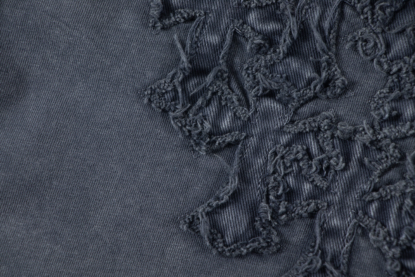 Close-up of dark embroidered floral patch detail on T-shirt fabric.