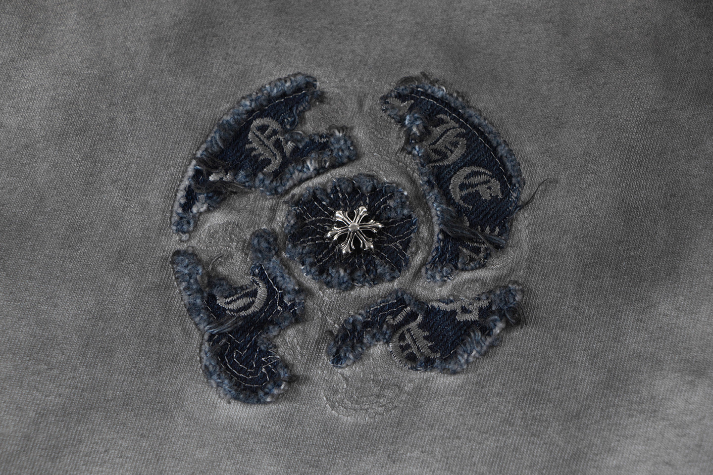 Embroidered emblem detail on T-shirt fabric in navy thread