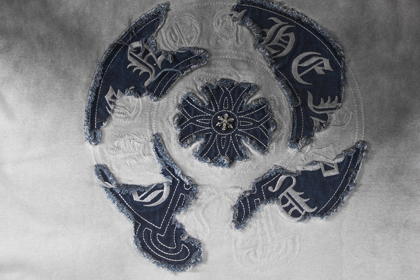 Close-up of navy embroidered crest on gradient T-shirt