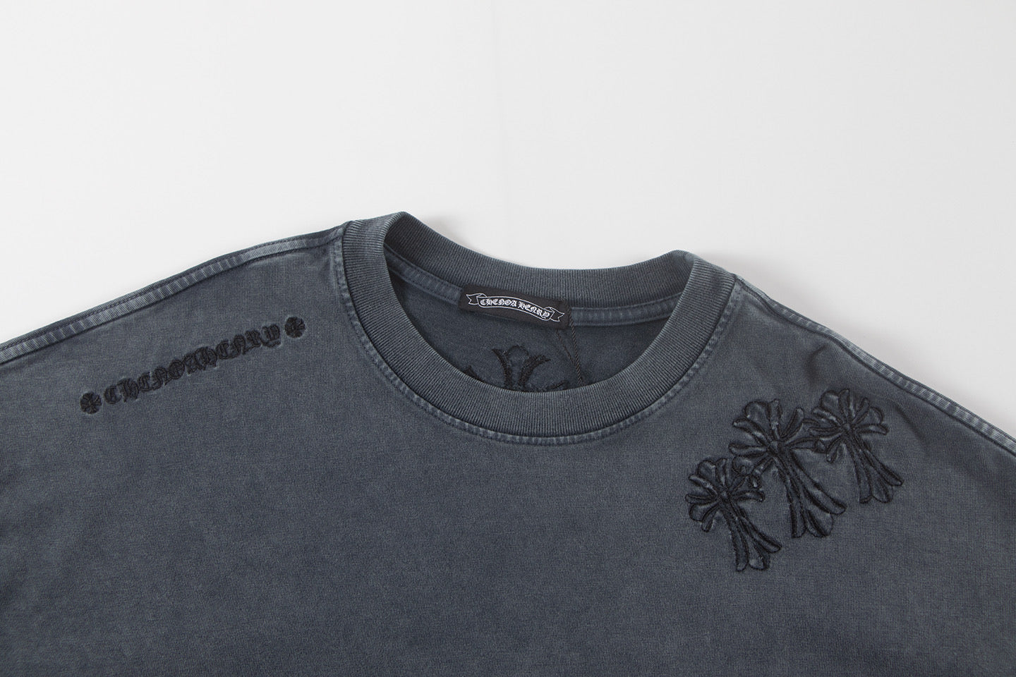 Dark gray graphic T-shirt with chest emblem and small flower detail