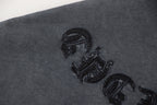 Close-up of dark gray graphic T-shirt fabric with embroidered symbol on sleeve
