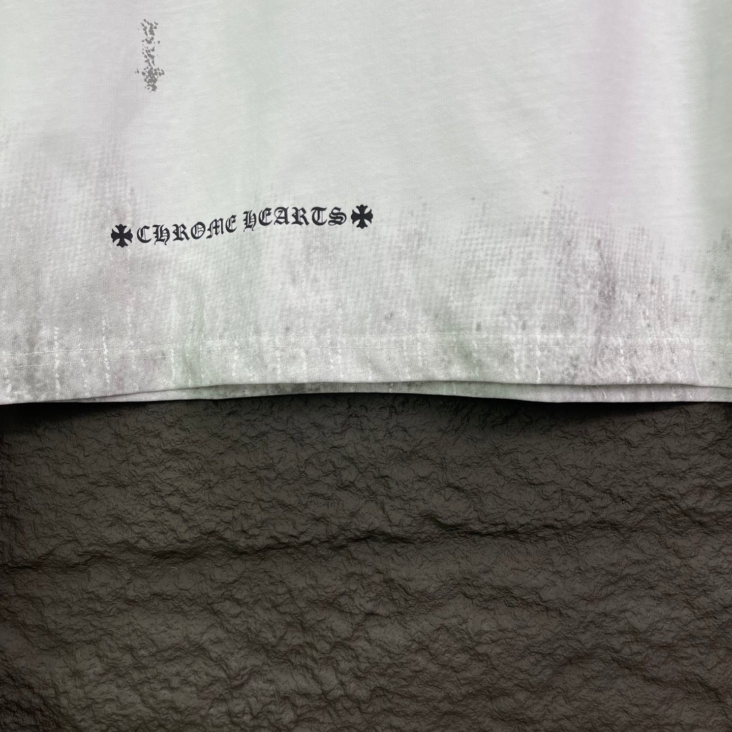 White short-sleeve T-shirt hem with distressed text-style graphic