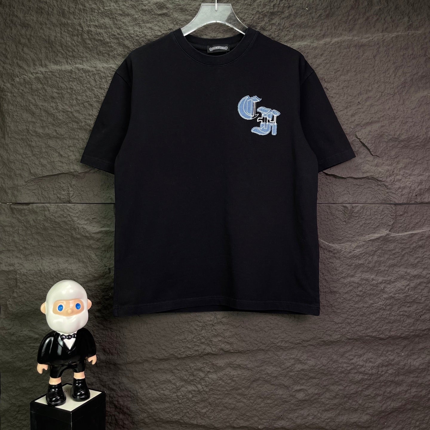 Black short-sleeve T-shirt with small light-blue logo graphic on chest