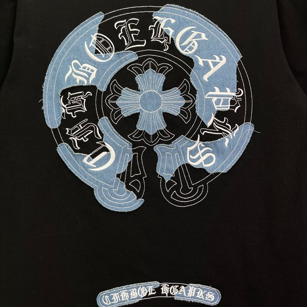 Black T-shirt with large circular embroidered light-blue graphic and text ribbon