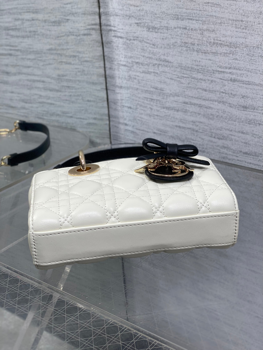 Quilted handbag side view with gold-tone hardware, black strap, and top bow detail
