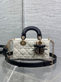 Quilted handbag with black leather top handles, bow emblem, and gold chain accents
