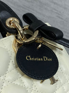 Quilted handbag charm tag reading "Christian Dior" with gold hardware and black bow