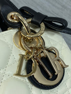 Quilted handbag clasp hardware with gold-tone rings and black leather bow strap