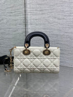 Quilted handbag with black leather handles, white body, and gold-tone rings at top