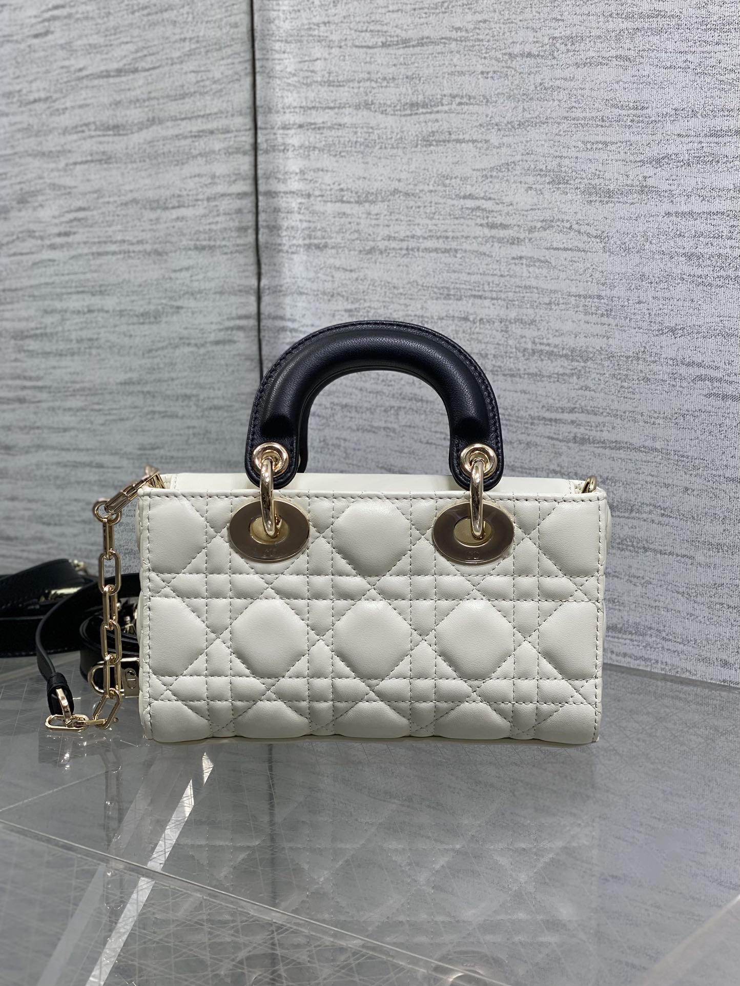 Quilted handbag with black leather handles, white body, and gold-tone rings at top