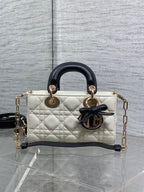 Quilted handbag with black handles, bow emblem, and gold-tone chain shoulder strap