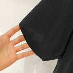 Black T-shirt fabric close-up with visible stitched hem and sleeve seam
