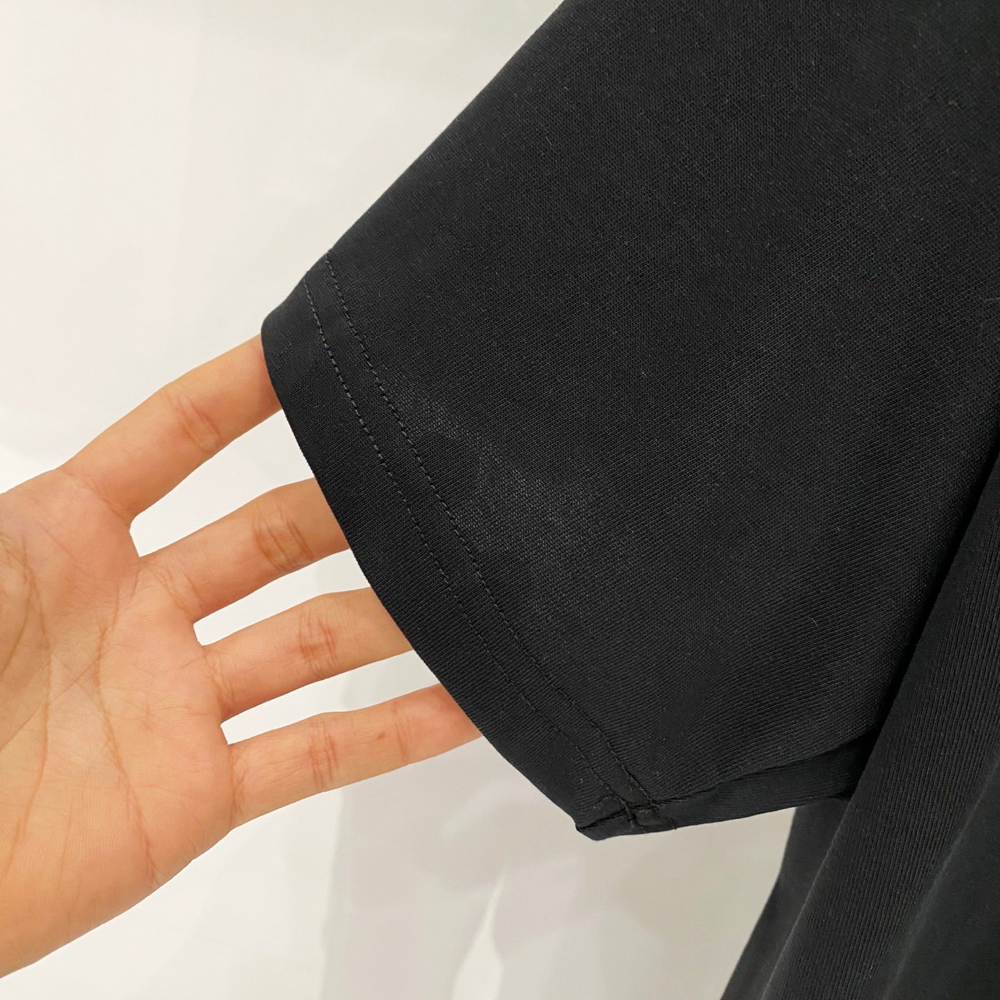 Black T-shirt fabric close-up with visible stitched hem and sleeve seam