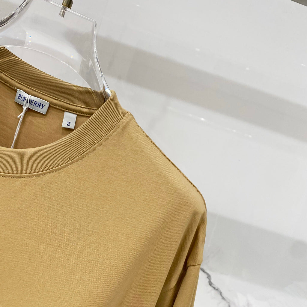 Tan short-sleeve T-shirt shoulder and sleeve detail on clear hanger