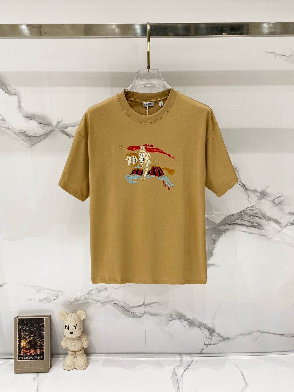 Tan short-sleeve T-shirt with multicolor cartoon horse graphic at center
