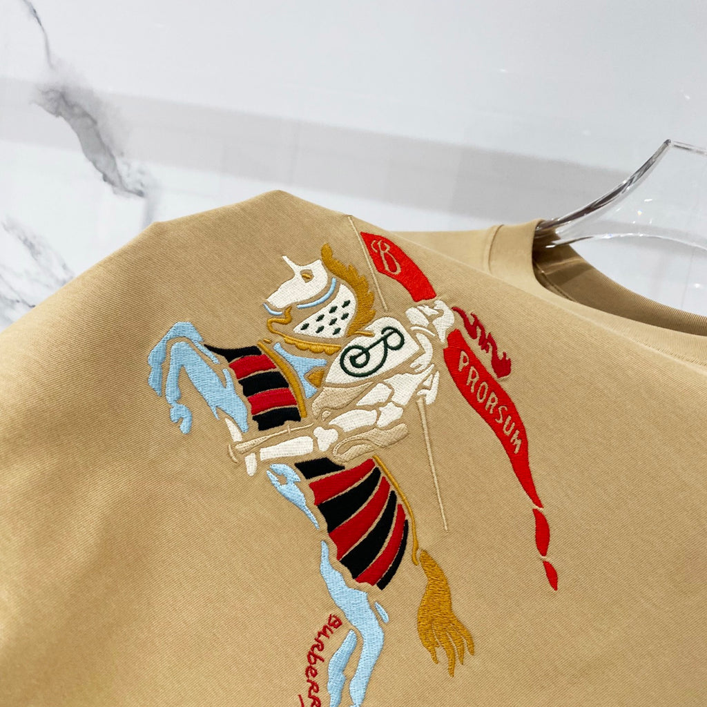 Tan T-shirt with large embroidered cartoon horse crest graphic on front