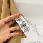 Tan T-shirt care label with Burberry tag attached near sleeve cuff