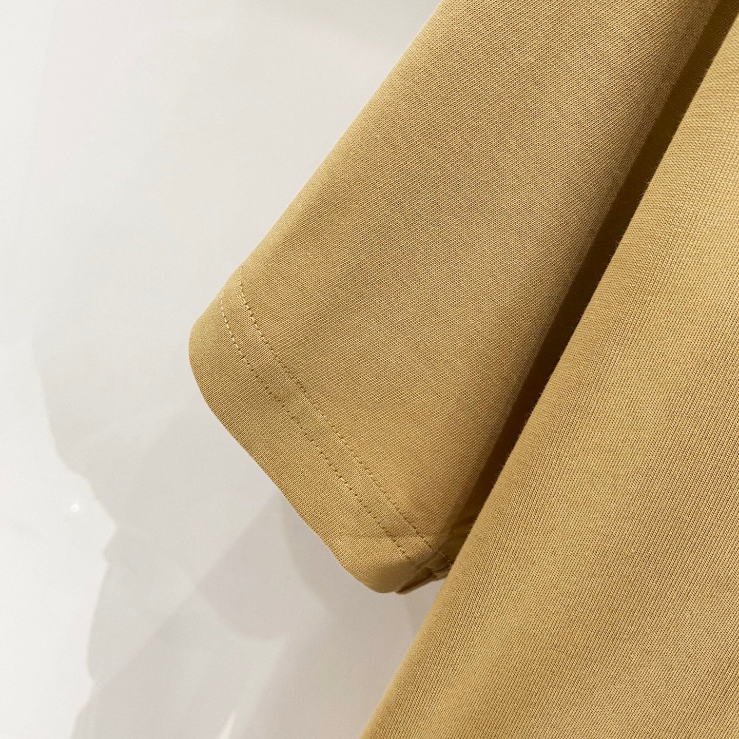 Tan T-shirt sleeve cuff and hem seam close-up