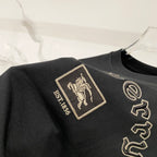 Black T-shirt with gold crest patch and EST.1885 embroidery detail