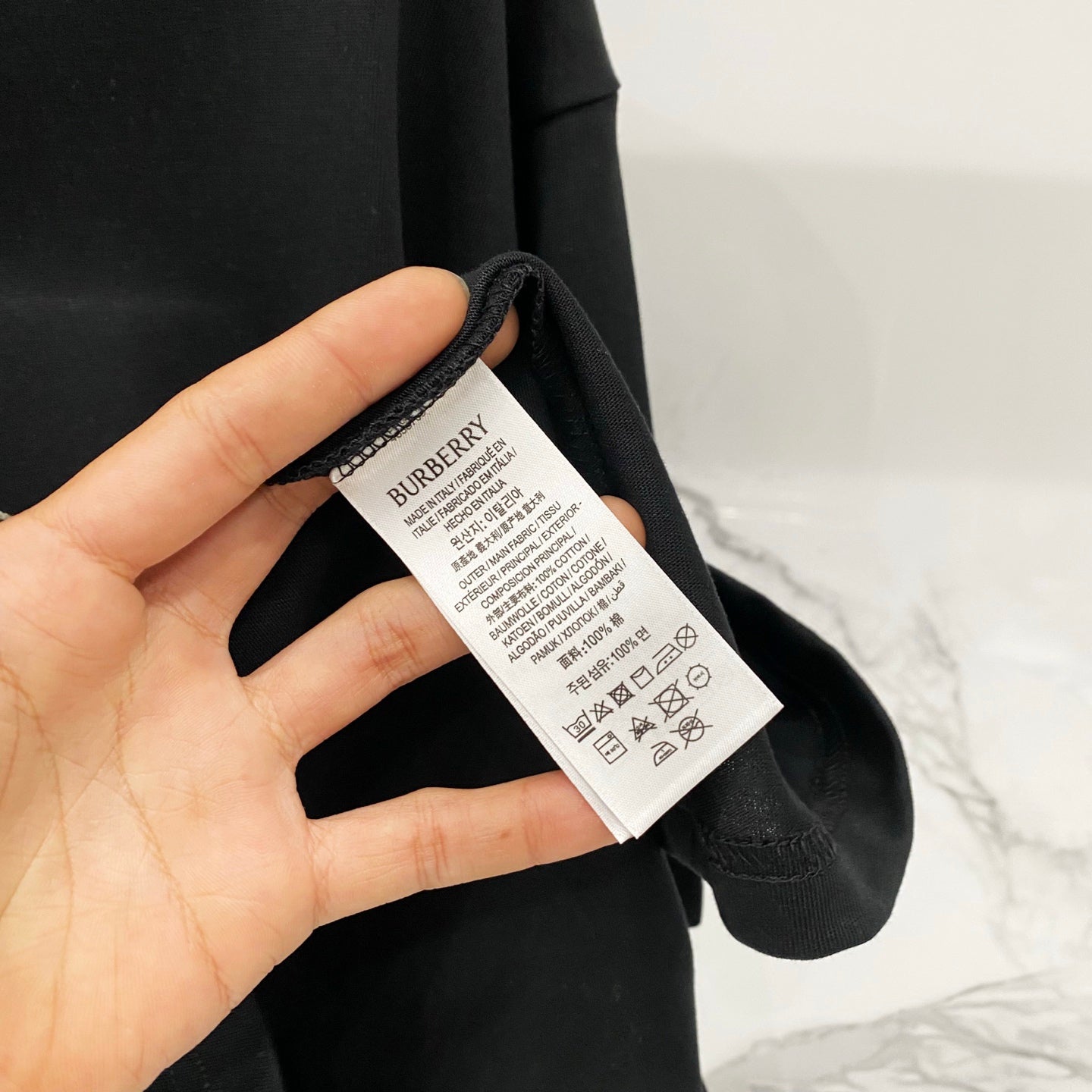Black T-shirt with white care label and size information tag