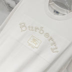 White T-shirt front with “Burberry” text-style embroidery and small crest patch