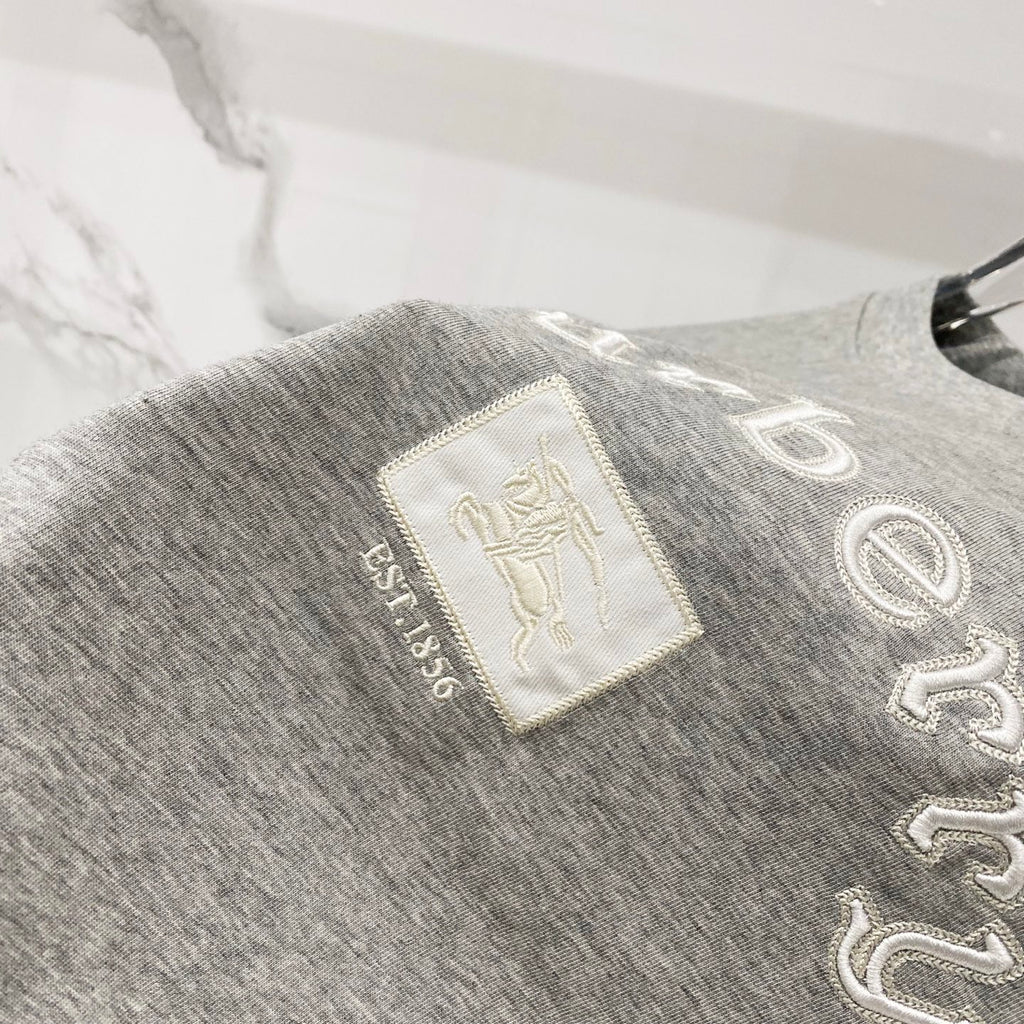 Grey T-shirt with embroidered “Burberry” text and small logo patch detail