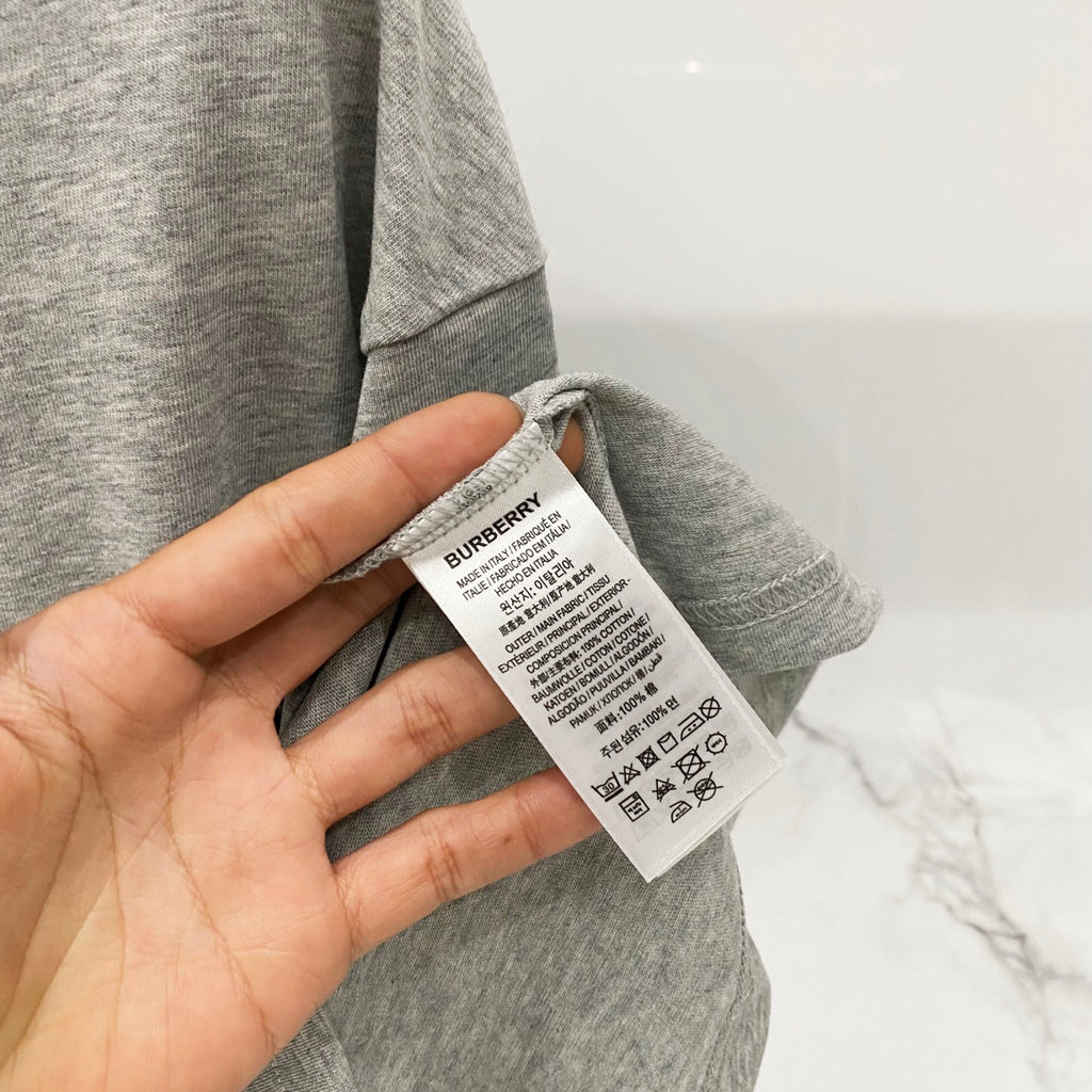 Grey T-shirt with fabric tag and care label near the side hem