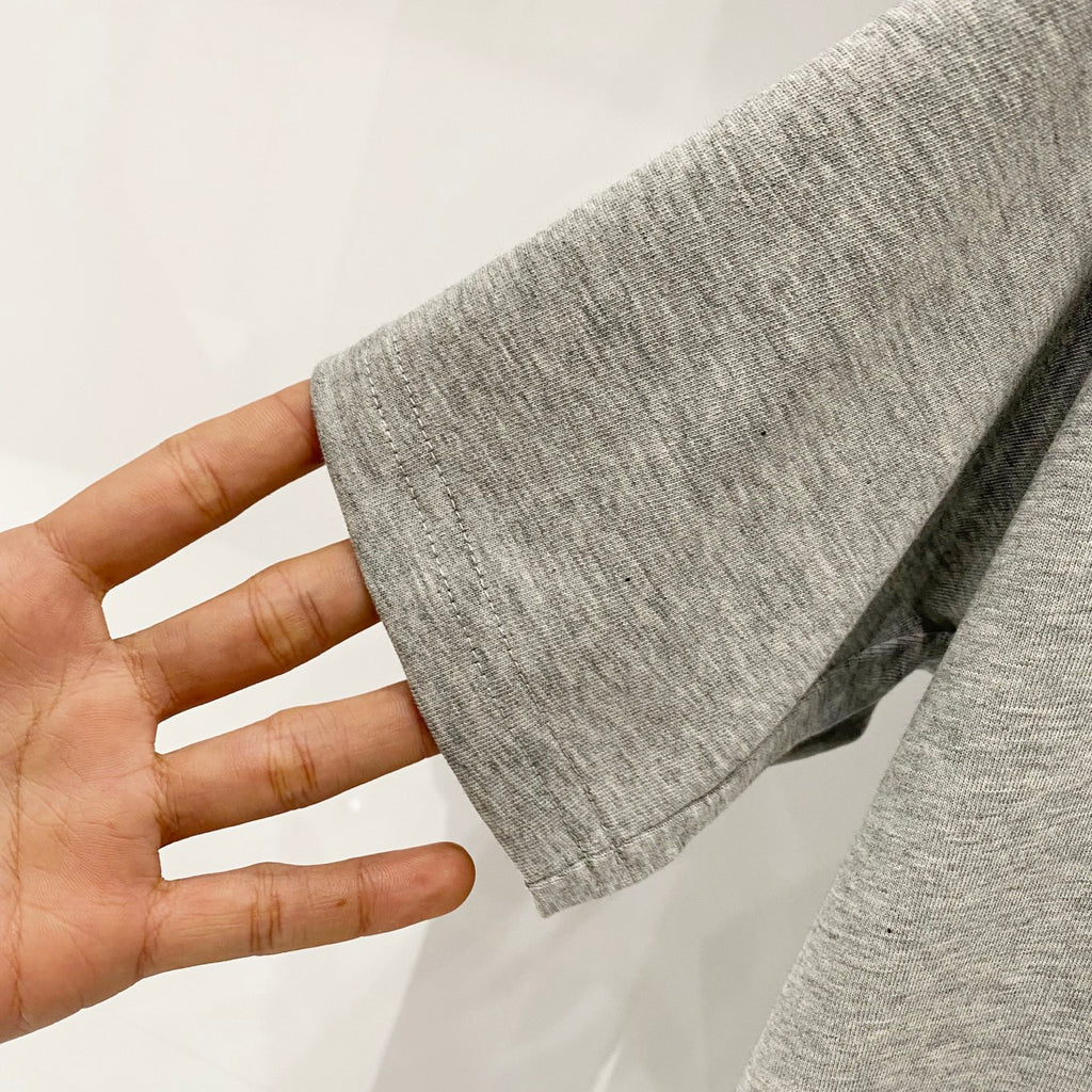 Grey T-shirt sleeve hem shown held in a hand