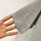 Grey T-shirt sleeve hem shown held in a hand