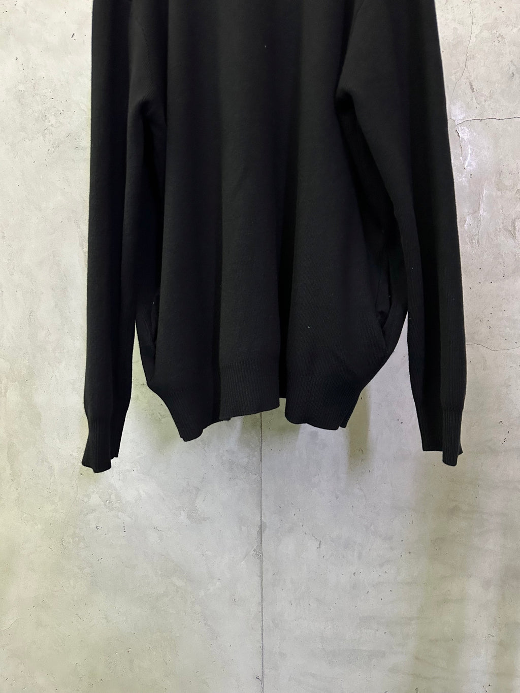 Black long coat back close-up with long sleeves and curved hemline